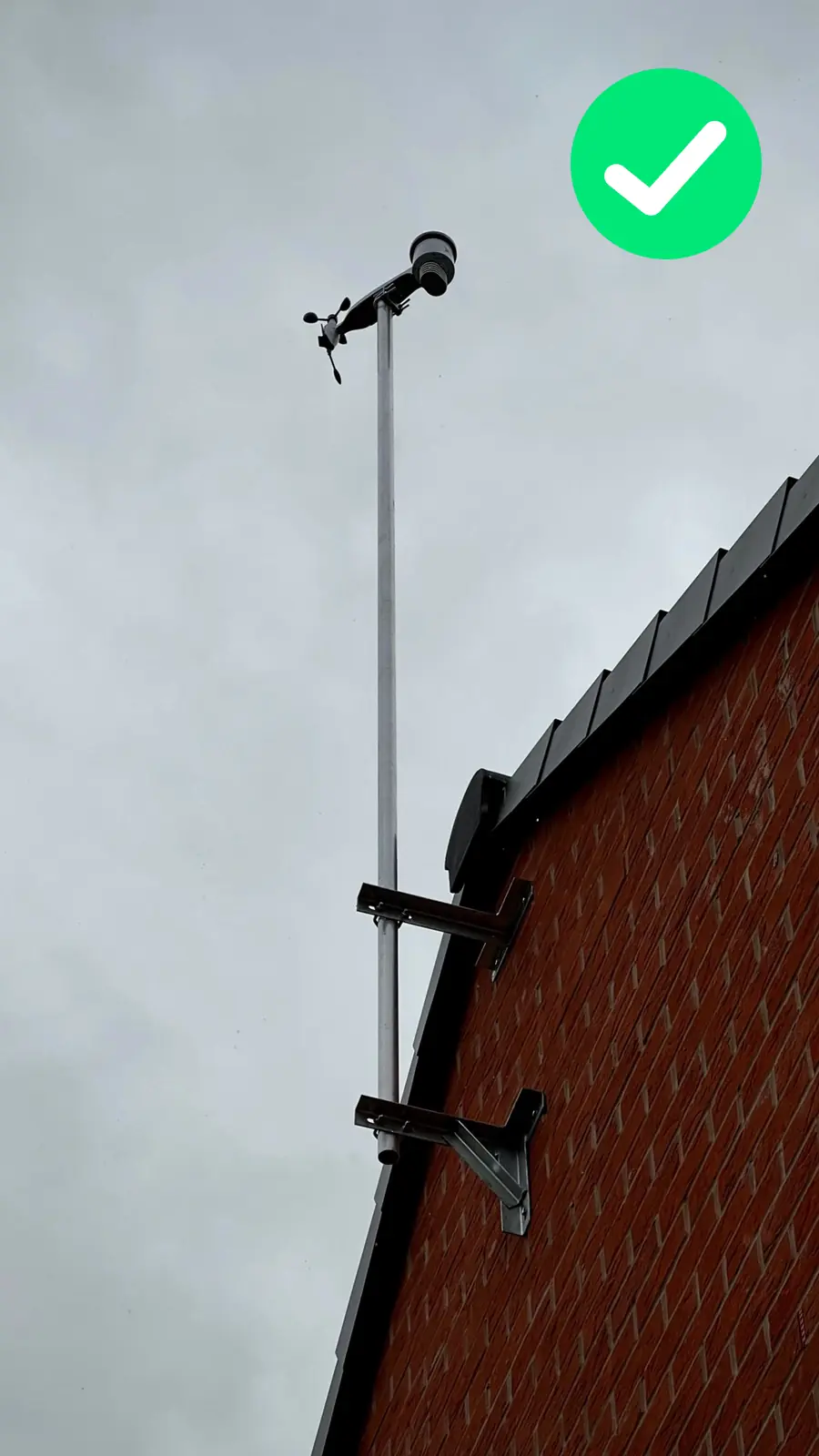 WeatherXM station installed high above an apartment roof on a tall mast